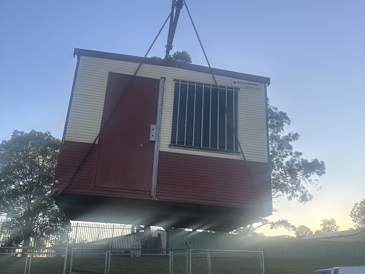 Crane truck lifting a site shed for Black Diamond at dusk